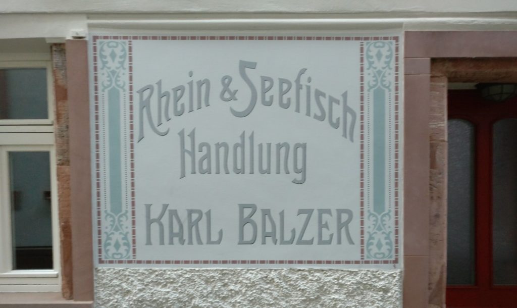 Die "Rhein- und Seefisch-Handling" von Karl Balzer gibt es schon lange nicht mehr. Wer im Internet recherchiert, findet keine Hinweise auf das frühere Unternehmen in Mainz. Als letzter Zeuge  des damaligen Glanzes findet sich dieses in den Putz eingearbeitete Firmenschild. Mainzer Wände am Haus der Fischergasse 10 künden von dem Geschäft des Karl Balzer.